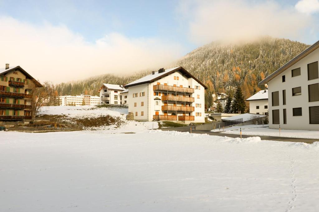 eine Gruppe von Gebäuden im Schnee mit einem Berg in der Unterkunft Etania in Davos