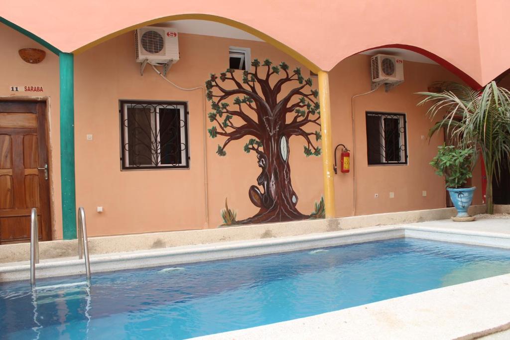 a house with a tree mural next to a swimming pool at Sall Africa Tourisme in Mbour
