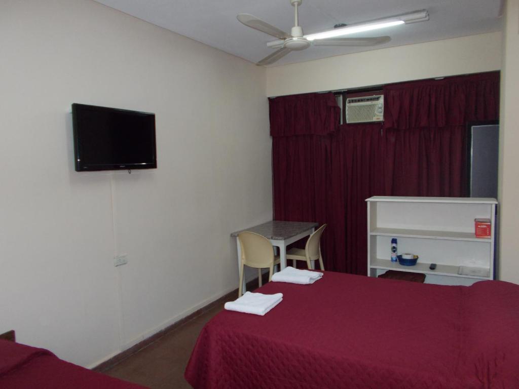 Habitación con cama y TV en la pared. en Apart Office en San Miguel de Tucumán