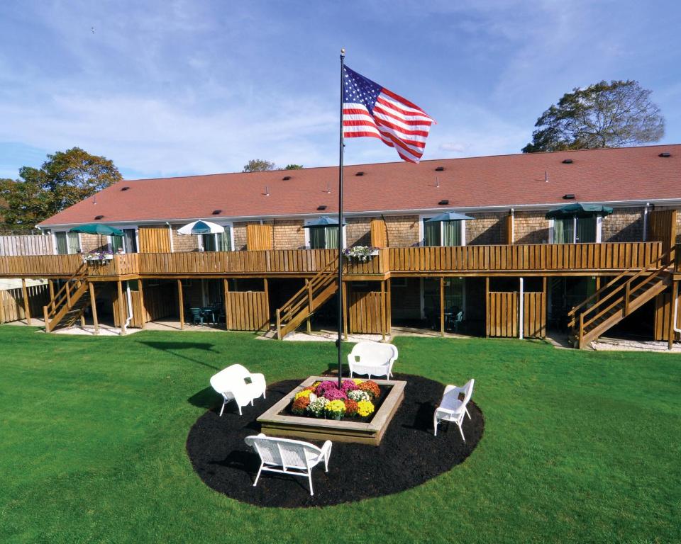 um alojamento de turismo selvagem com uma bandeira, uma mesa e cadeiras em Cape Winds Resort, a VRI resort em Hyannis