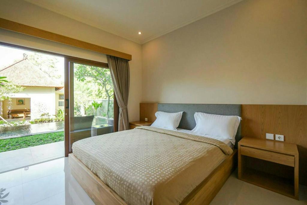 a bedroom with a bed and a large window at Arnaya Homestay in Kuta