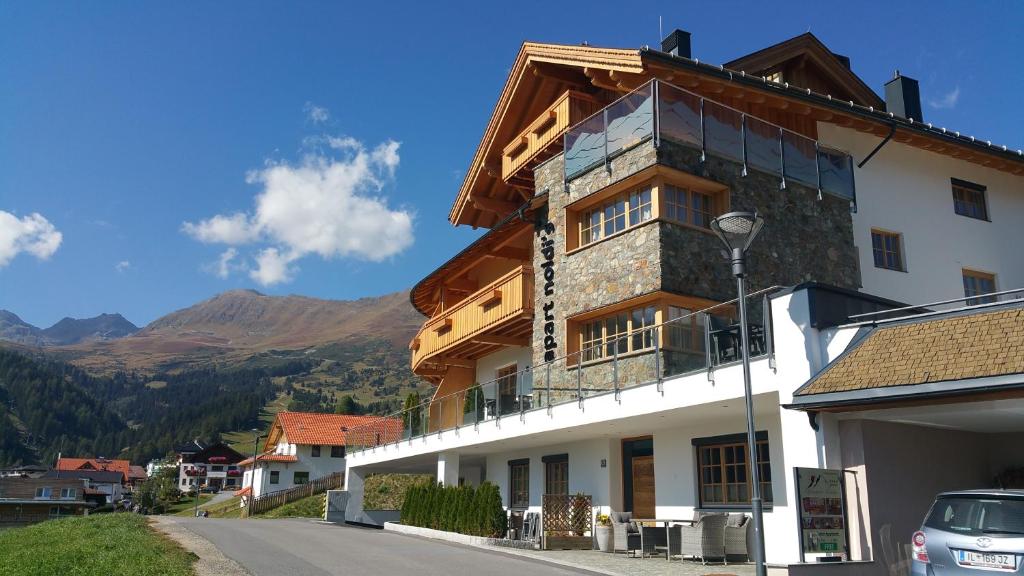 a building on a street with mountains in the background at Noldis Apart in Serfaus