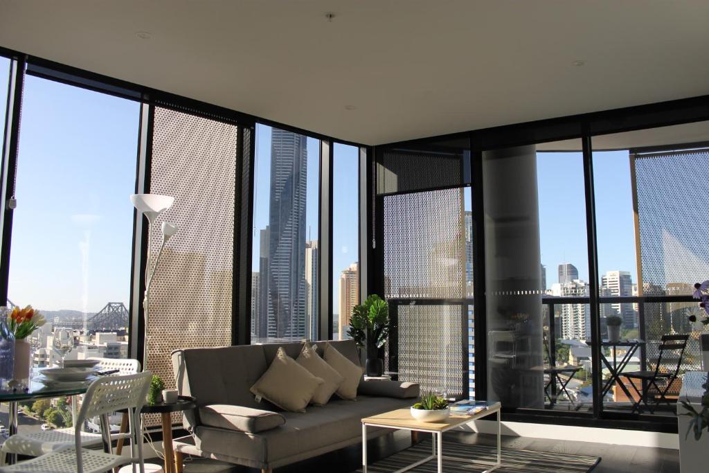 a living room with a couch and large windows at Spectacular Views of CBD by FV with Free Car Park in Brisbane