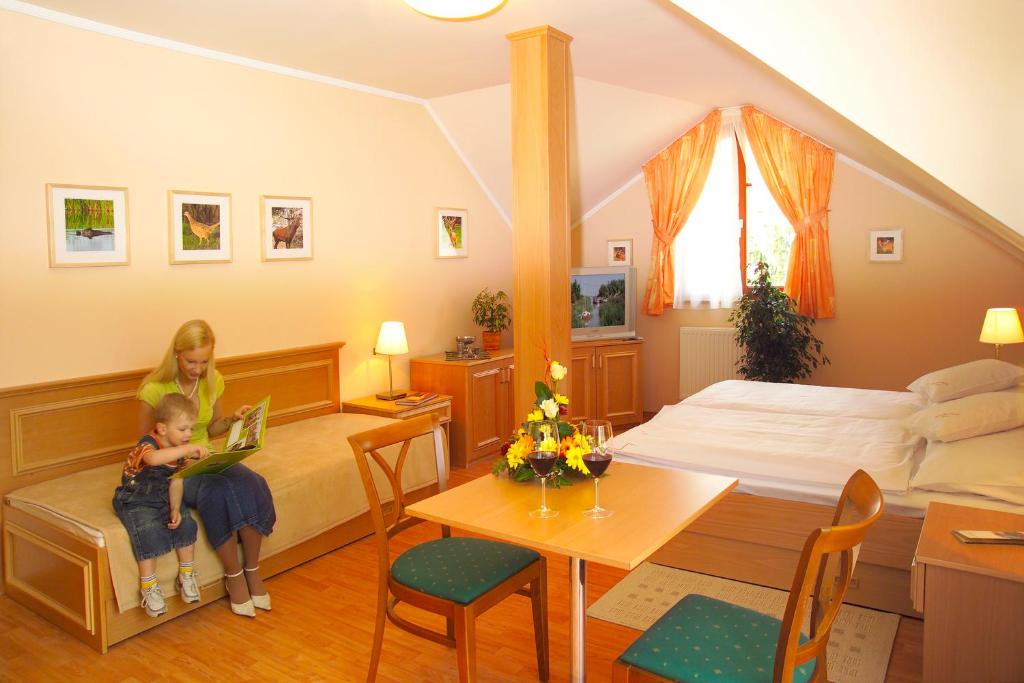 a woman and a child sitting in a bedroom at Vadászkürt Panzió és Étterem in Sopron