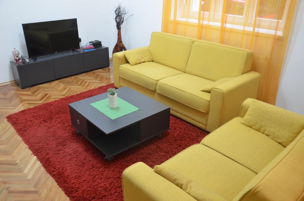 a living room with two yellow couches and a tv at Sarajevo City Center in Sarajevo