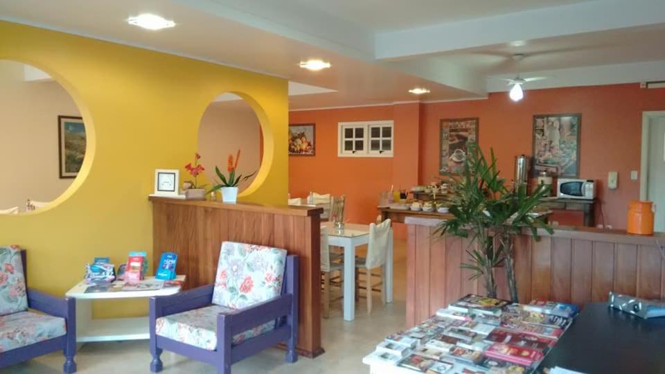 un salón con paredes de color naranja, mesa y sillas en Pousada Recanto Alpino, en Gramado