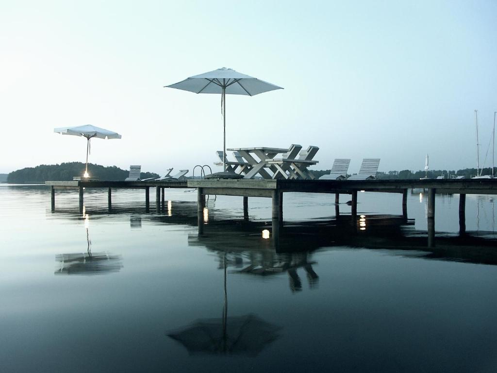 a dock with chairs and an umbrella on the water at Galery69 in Dorotowo