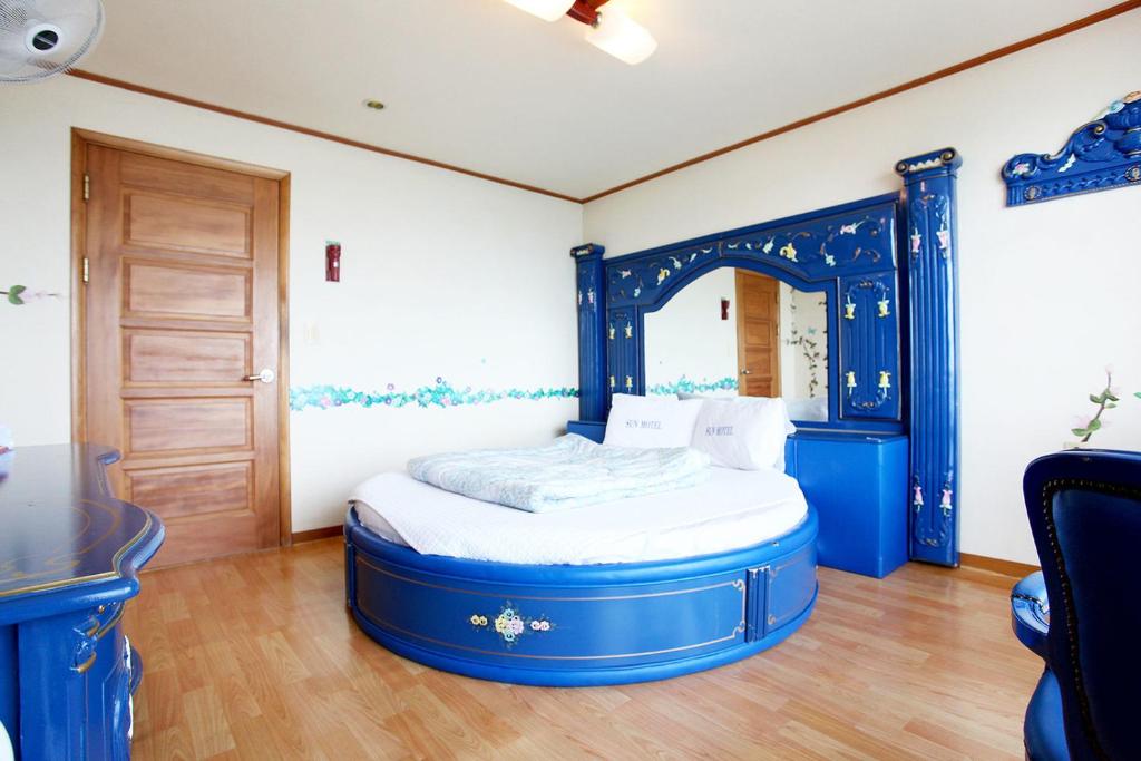 Cama azul en habitación con mesa en Sun Motel en Gangneung