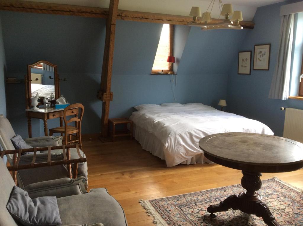 a bedroom with a bed and a table and chairs at Haras de Baudemont in Ittre