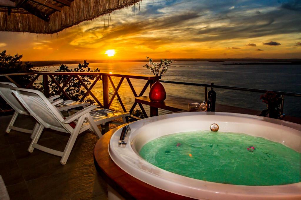 a jacuzzi tub on a balcony with a sunset at Mar e Morro Flats in Morro de São Paulo