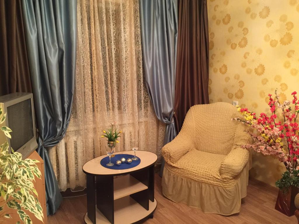 uma sala de estar com uma cadeira e uma mesa em Апартаменты на Вихрева, 82 em Shuya