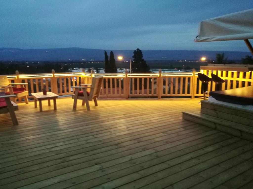 una terraza de madera con mesa y sillas. en ronit's place en Qiryat Shemona