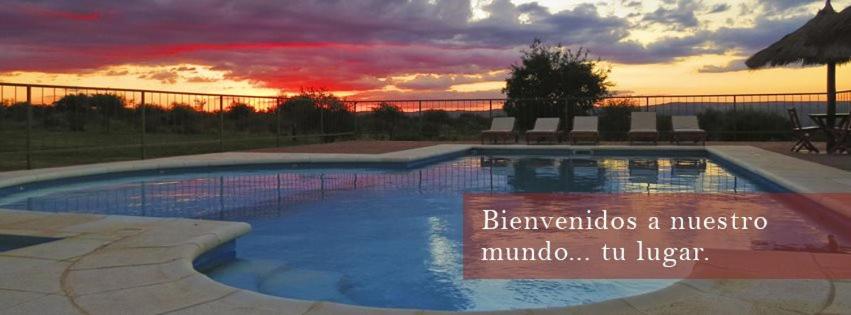 a large swimming pool with a sunset in the background at Dos Soles in Mina Clavero