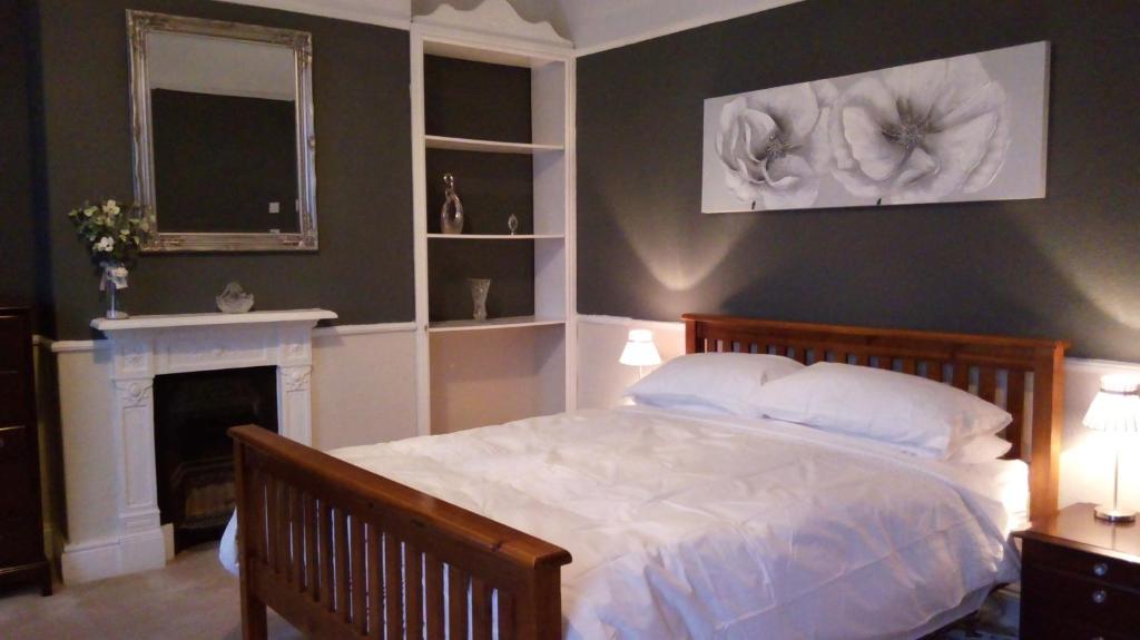 a bedroom with a white bed and a fireplace at Stonehouse Apartment in Mexborough