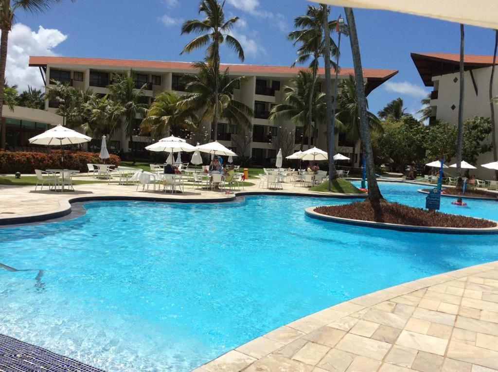 een groot zwembad met blauw water voor een hotel bij Marulhos Resort Flat Particular in Porto De Galinhas