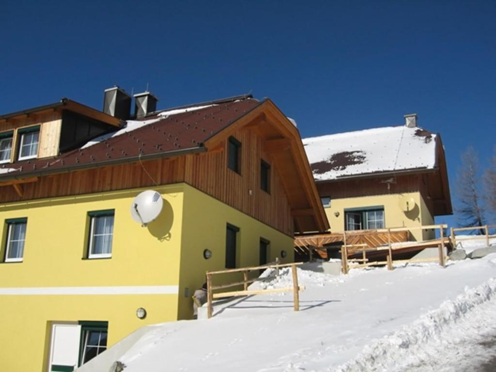 レンヴェークにあるKatschberg Appartementsの雪褐色の屋根の黄色い建物