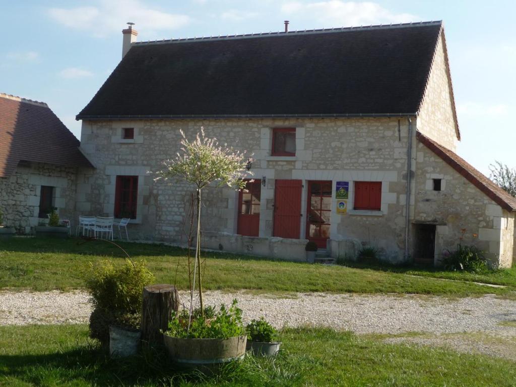 een stenen huis met een boom ervoor bij La maison des fleurs in Saint-Senoch