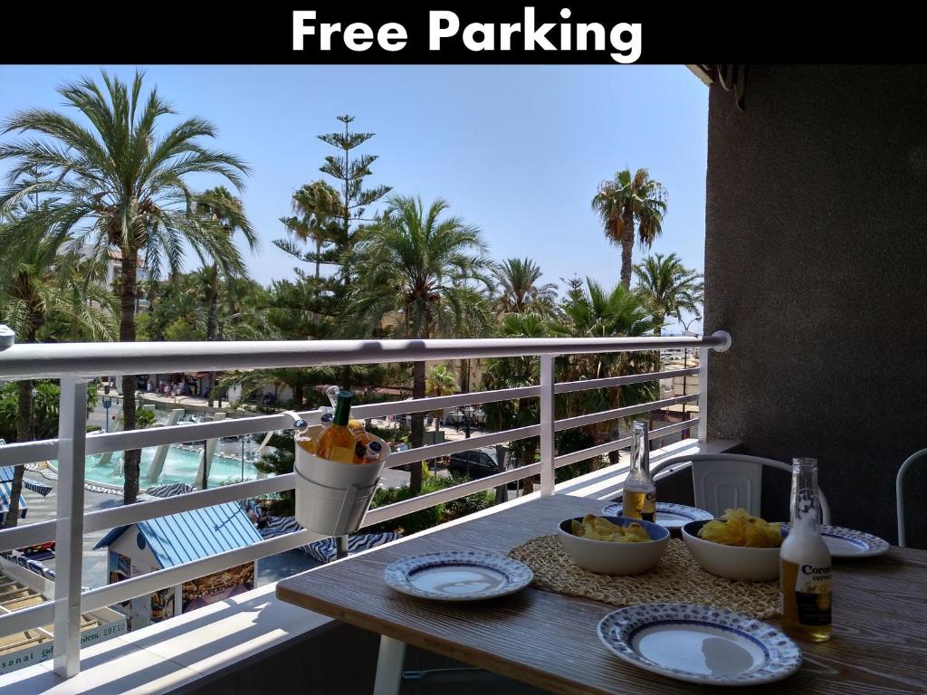 a table with plates of food on a balcony with palm trees at Apartamento Chapaprieta 1 in Torrevieja