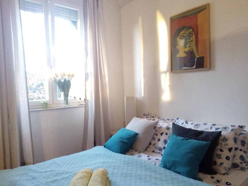 een slaapkamer met een bed met blauwe kussens en een raam bij Apartment Optimist/City Break in Split