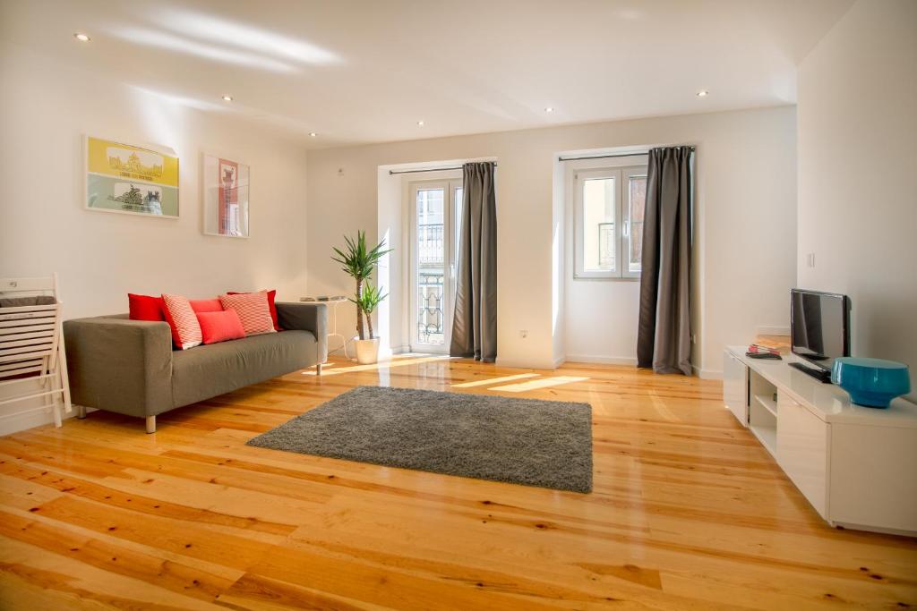 ein Wohnzimmer mit einem Sofa und einem TV in der Unterkunft Bica Historical Tram Apartment in Lissabon