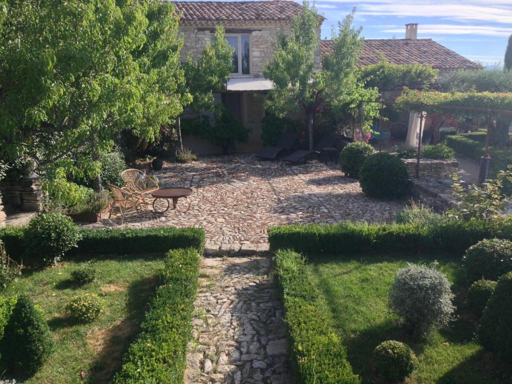 um jardim com uma mesa e um banco em frente a uma casa em PROVENCEguesthouse L'Agace em Forcalquier