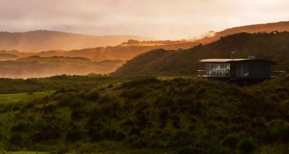 une maison au sommet d'une colline dans un champ dans l'établissement Mures Cloudy Bay Retreat, à South Bruny
