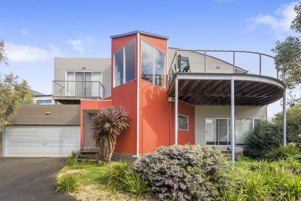 an orange house with a balcony on top of it at Seaside Pleasure in Apollo Bay