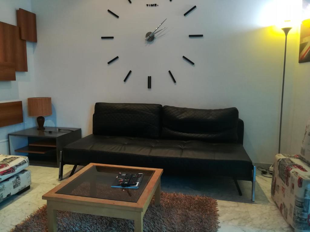uma sala de estar com um sofá e um relógio na parede em Loft Aziz em Tunes