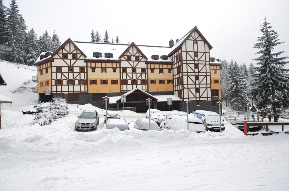 a large building with cars parked in the snow at Apartmany Alectis in Pec pod Sněžkou