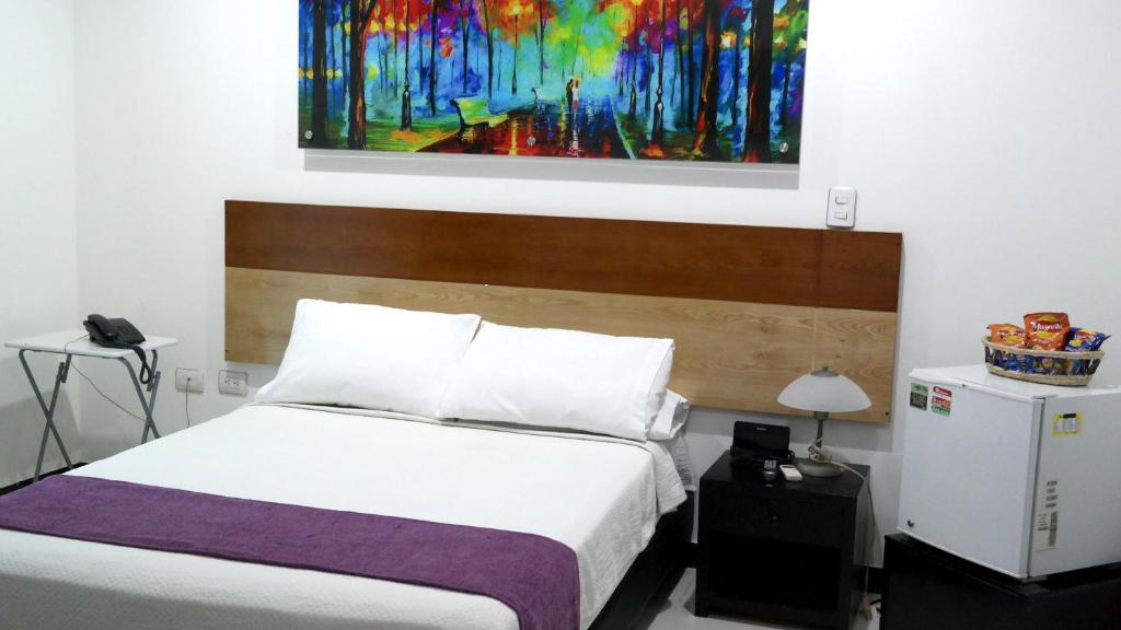 a bedroom with a bed with a painting on the wall at Hotel Sama in Montería