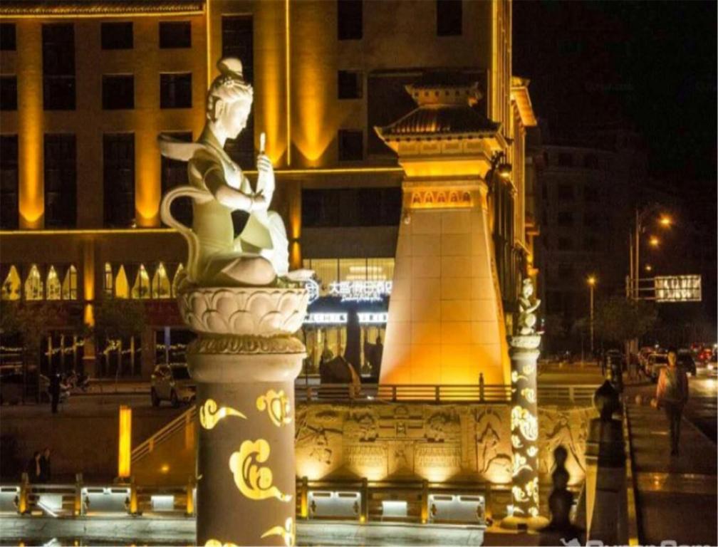 una estatua de una mujer sentada sobre un monumento en Dunhuang Dasheng Vacation Hotel, en Dunhuang