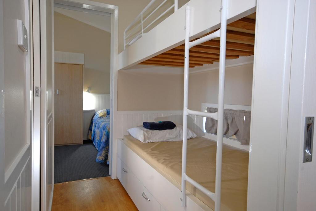 Barrack Point的住宿－百瑞可度假村，一间设有白色双层床的房间和一间卧室