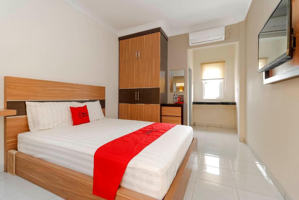 a bedroom with a large bed with a red blanket at RedDoorz Plus near Palembang Square Mall in Palembang