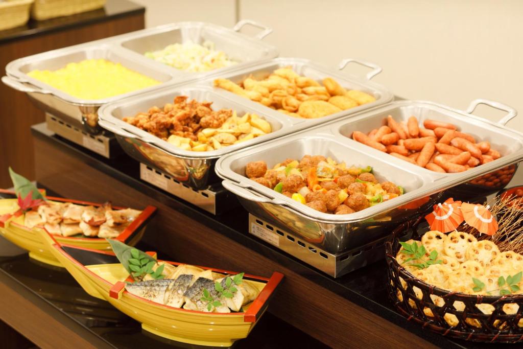 a buffet with several trays of different types of food at HOTEL MYSTAYS Kanazawa Castle in Kanazawa