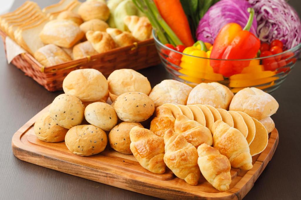 a cutting board with bread and vegetables on a table at HOTEL MYSTAYS Kanazawa Castle in Kanazawa
