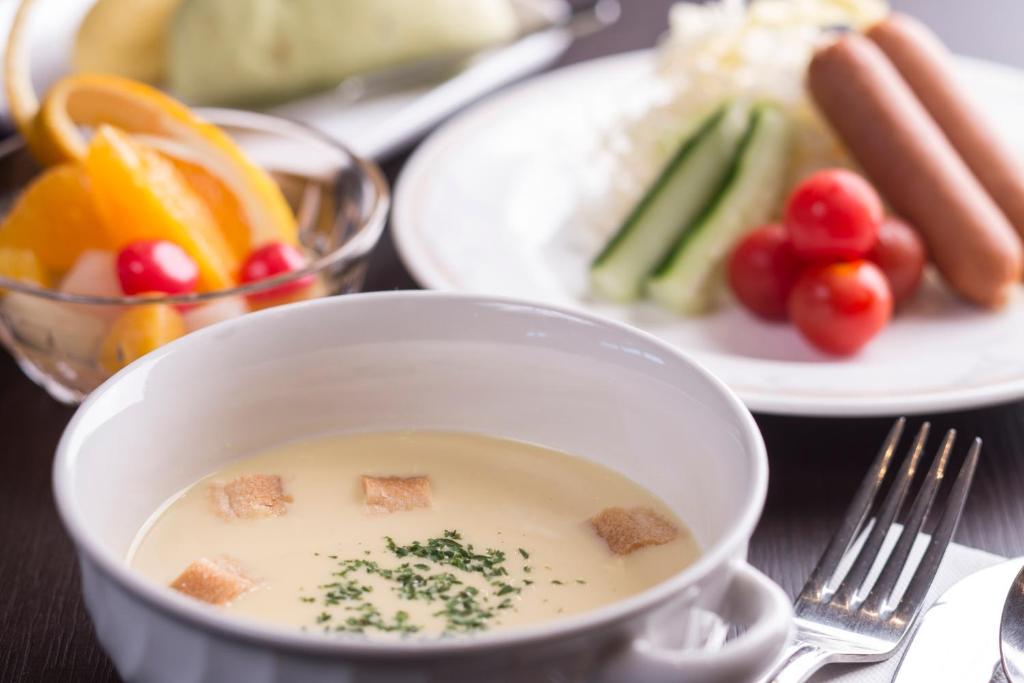 a bowl of soup with vegetables and a plate of food at HOTEL MYSTAYS Kanazawa Castle in Kanazawa
