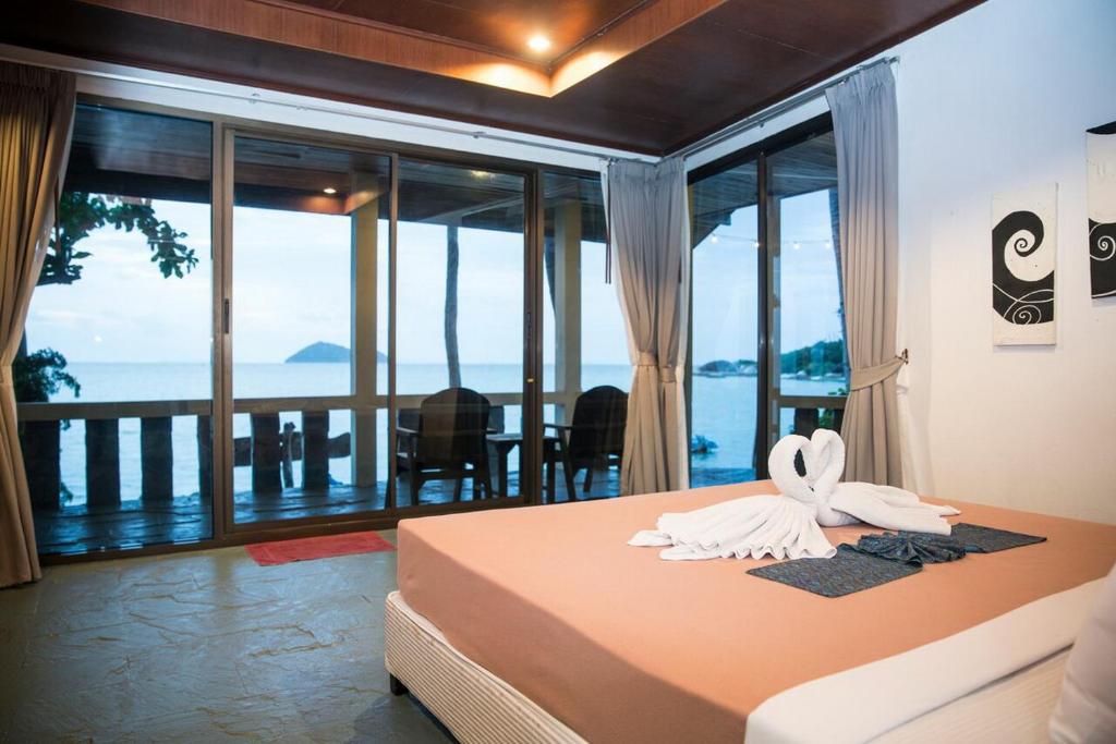 a bedroom with a bed with a view of the ocean at Beck's Resort in Haad Pleayleam