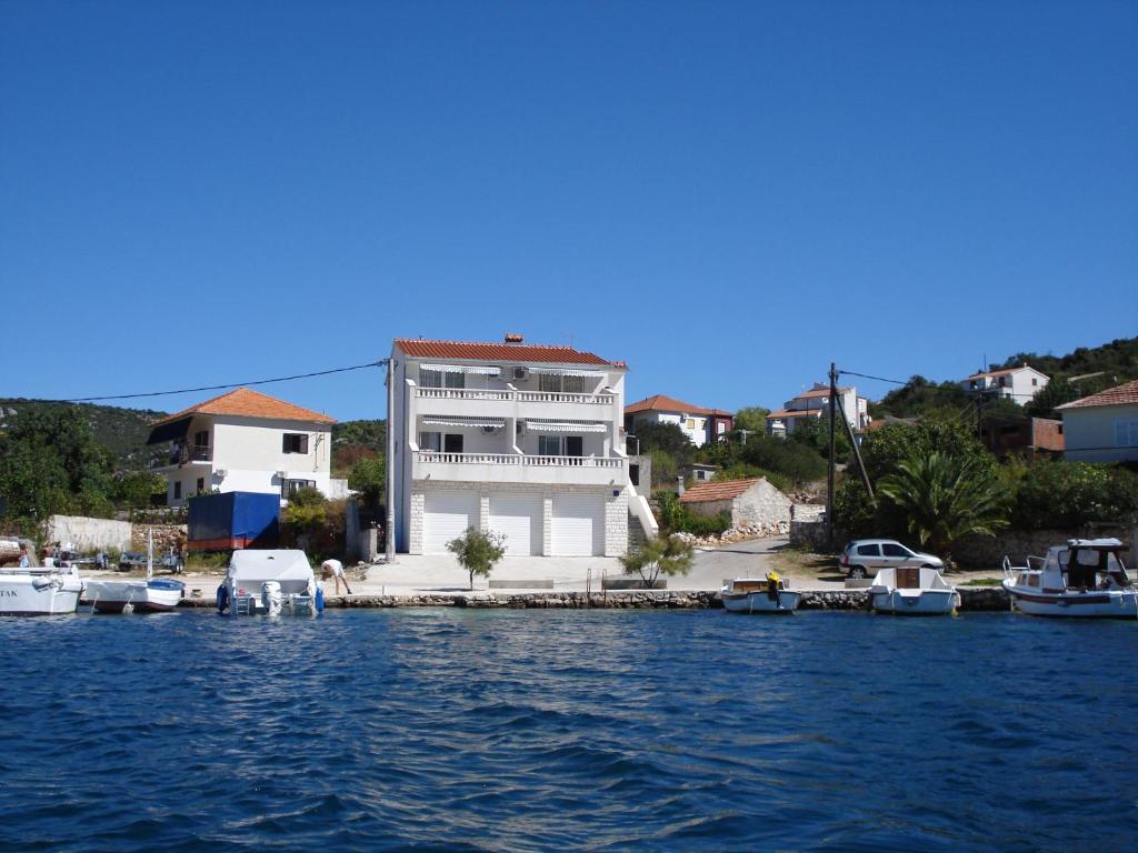 a house on a dock with boats in the water at Apartments Mirko in Vinišće