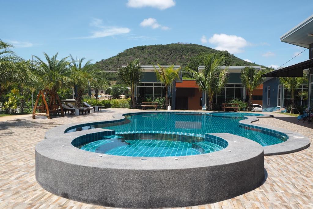 uma piscina em frente a um edifício com uma montanha em Mountain View resort em Pran Buri