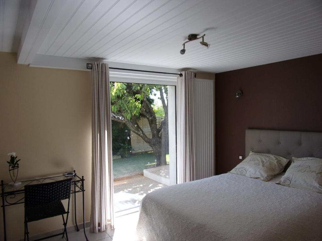 ein Schlafzimmer mit einem Bett und einem großen Fenster in der Unterkunft Maison d'hôtes Fortin Anita et Guy in Pouzauges