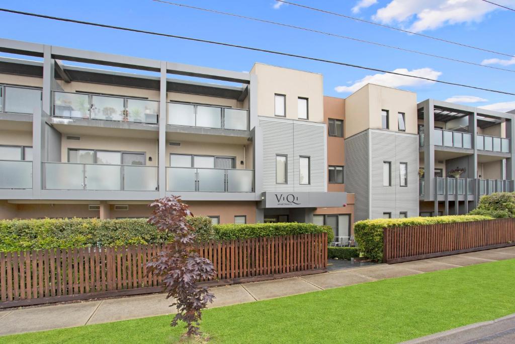 an apartment building with a fence in front of a yard at Astra Apartments Glen Waverley @ViQi in Glen Waverley