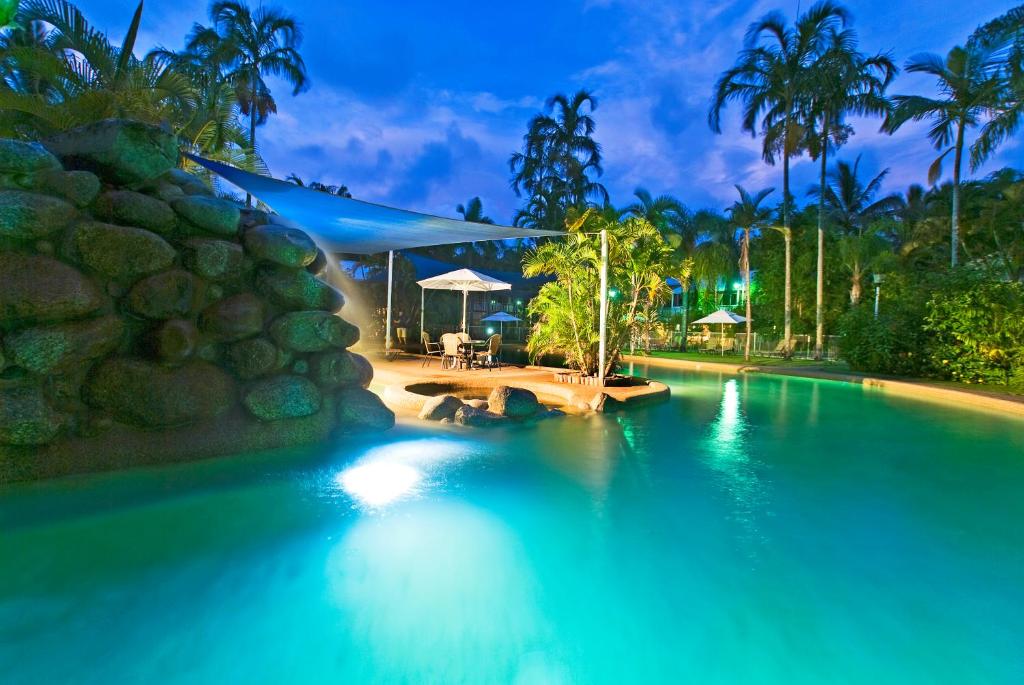 a swimming pool at a resort at night at Nimrod Resort Apartments in Port Douglas