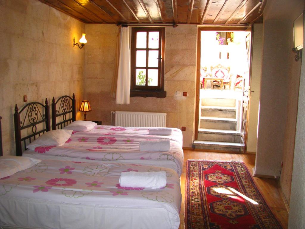 a bedroom with two beds and a window and a door at Nature Park Cave Hotel in Goreme