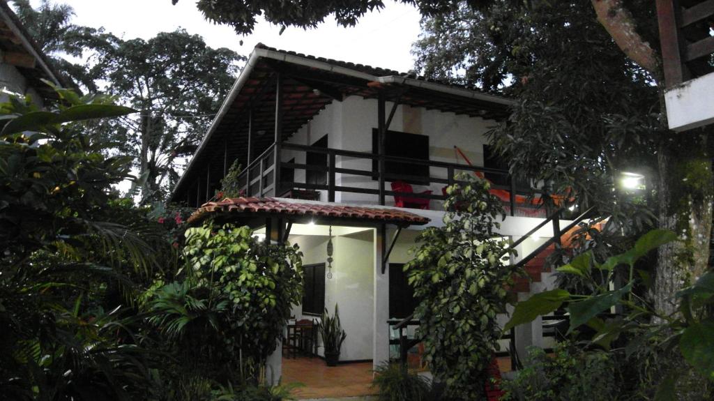 a white house with a balcony in a forest at Pousada Casa da Edinha in Ilha de Boipeba