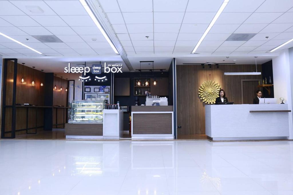 a woman standing at a desk in a lobby at Sleep Box by Miracle -Booked on Hourly Basis in Bangkok