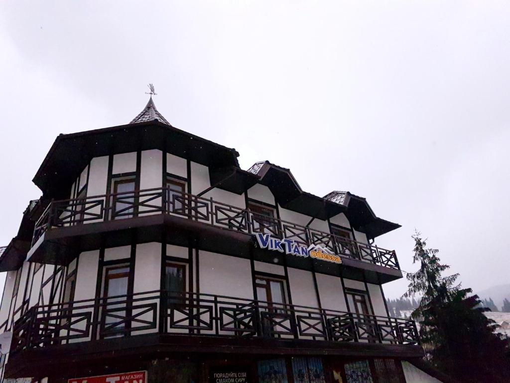 Ein hohes weißes Gebäude mit einem Schild drauf. in der Unterkunft Viktan Hotel in Bukowel