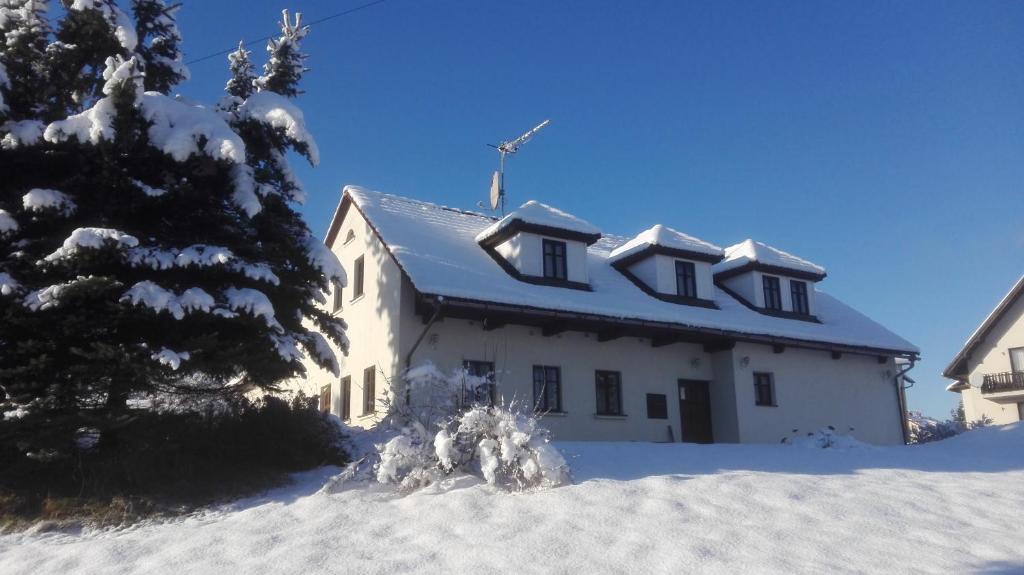 Biały dom z śniegiem na dachu w obiekcie Restaurace a penzion Jilm w mieście Jilemnice