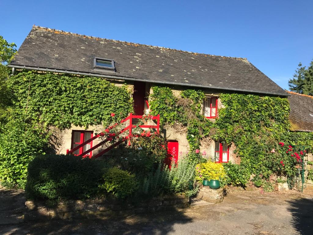 uma casa coberta de hera com portas e janelas vermelhas em Le Châtel em Riec-sur-Bélon