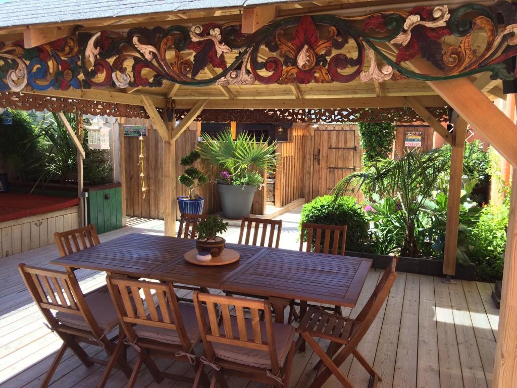 a wooden table and chairs on a deck with a stained glass ceiling at VILLA ZENITH Hostel - LA MAISON in Lacanau