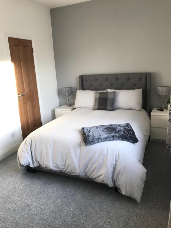 een slaapkamer met een groot bed met witte lakens bij Dunelm Snug in Seahouses